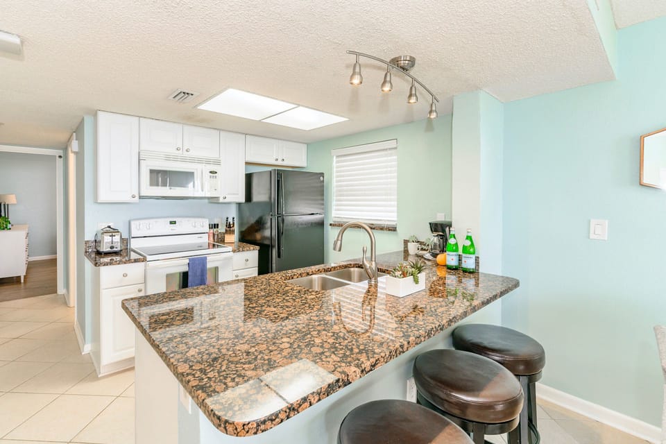 Open kitchen area, equipped with everything you need to make meals in the unit, featuring granite countertops and bar seating.