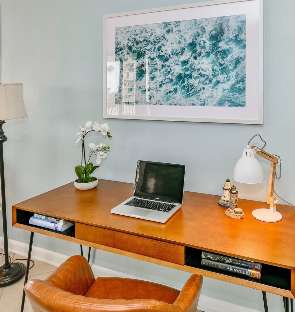 A stylish home workspace featuring a sleek desk, laptop setup, and decorative accents.