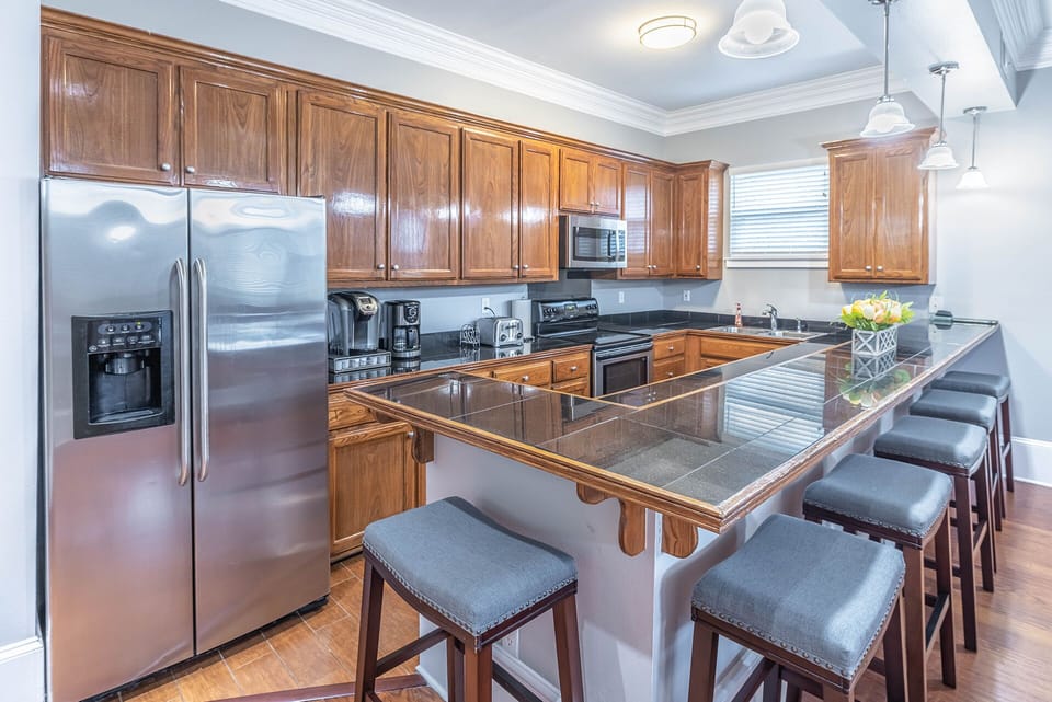 Kitchen view with barstools, double refrigerator, electric stove and microwave