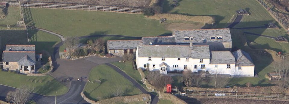 Aerial photo of the farmhouse and cottages at EAST ROSE - Mowhay to the far left