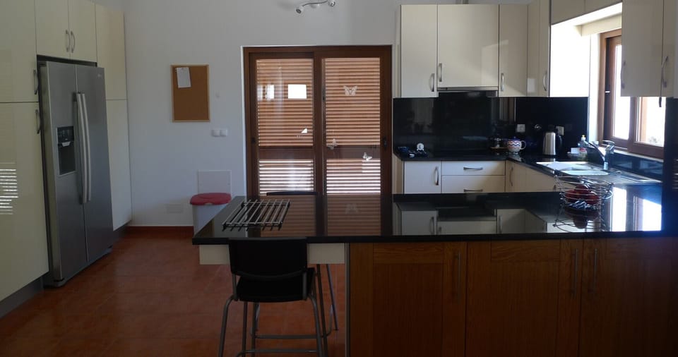 Kitchen with patio door and shutters to terrace. Breakfast bar with two chairs