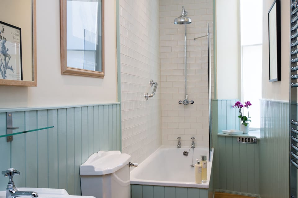 The bathroom with shower over the bath