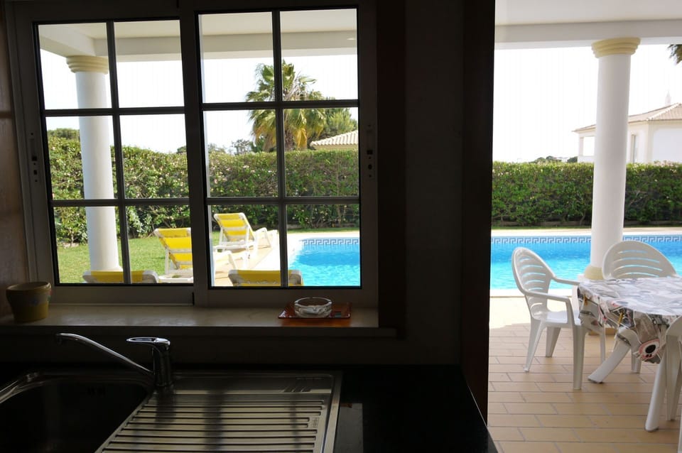 View from the fully equipped kitchen, to terrace, pool, gardens, lawn & sea views