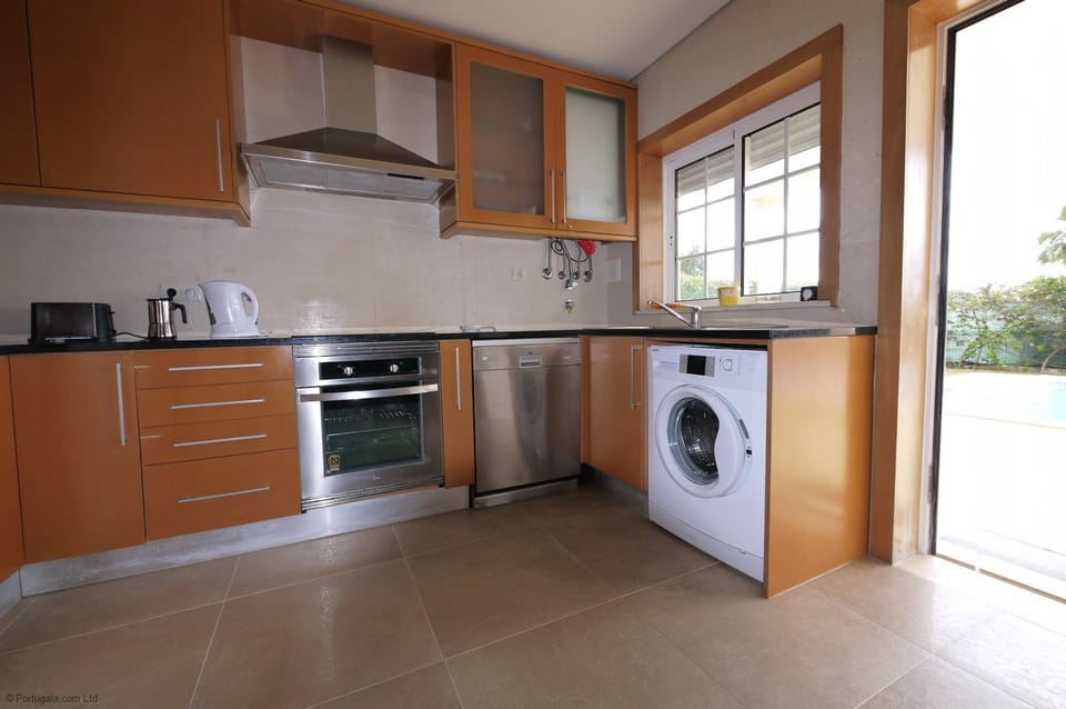Fully equipped kitchen overlooks the pool, terrace, lawn, garden & sea views.