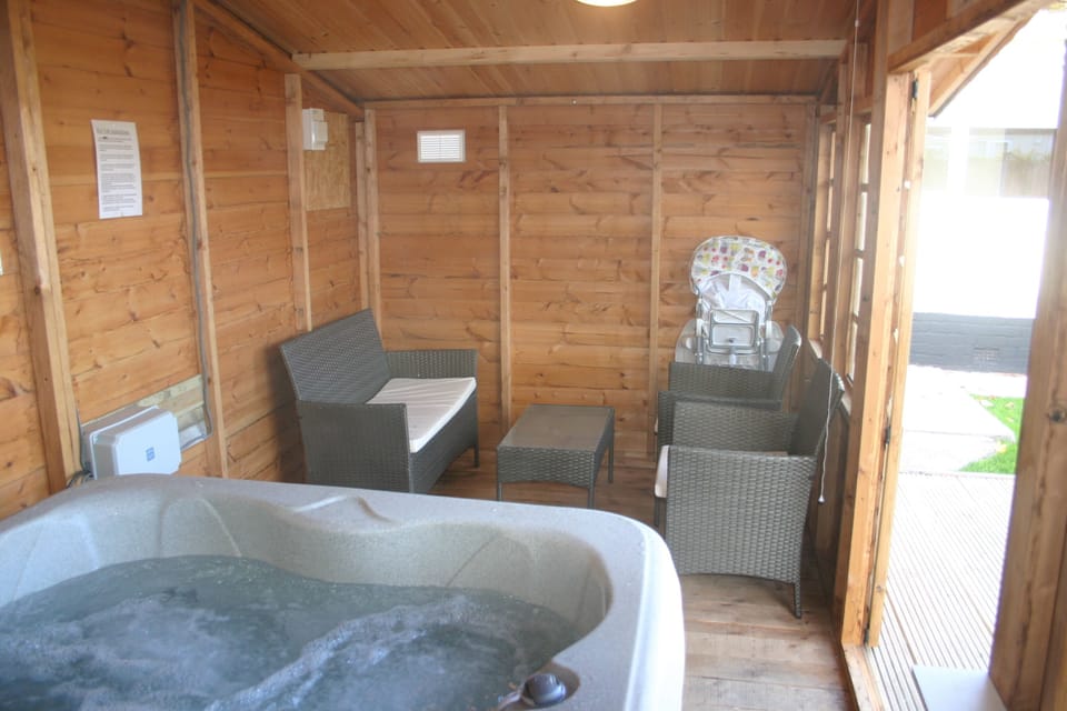 INSIDE SUMMER HOUSE WITH HOT TUB AND SEATING FOR GUESTS 
