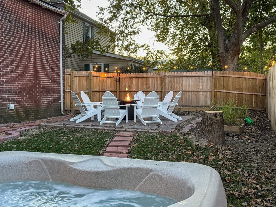 Private fenced in yard with propane fire pit, and stone walkway between hot tub and patio.