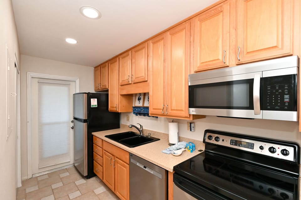 Modern, renovated kitchen, opens to living/dining area and window/door overlooking the bay and boat docks