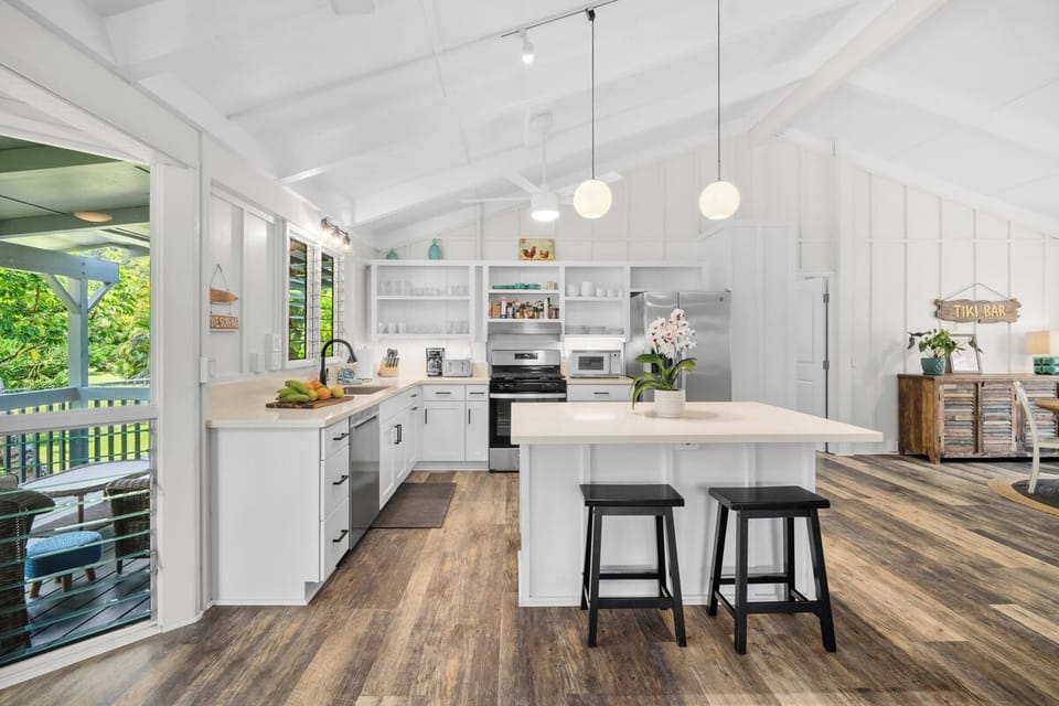 From the far end, the kitchen reads open and unfussy, wood floors running toward the light.