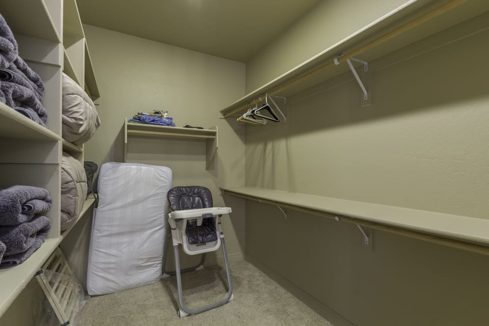 master closet with high chair, toddler bed, baby gate, and bath towels