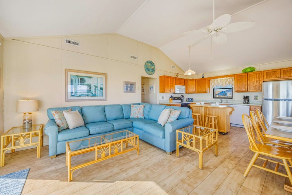 Unwind in your open-concept living space where coastal blue sectional seating flows seamlessly into a bright kitchen with island.