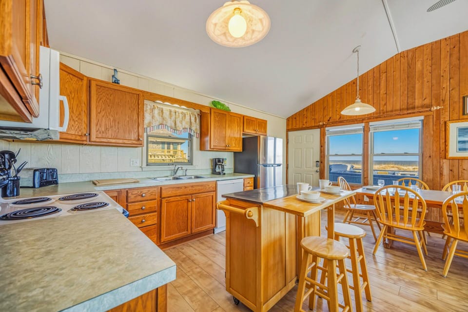 Step into your charming kitchen where warm wood tones create a cozy atmosphere for preparing meals while enjoying stunning water views through the windows.