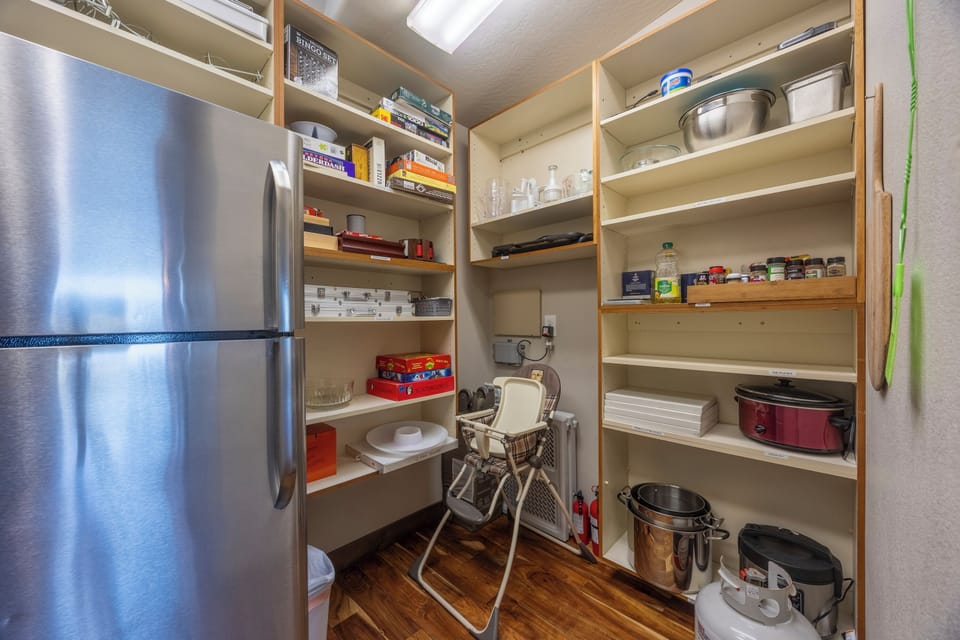 The pantry has an additional refrigerator, big pots, appliances, and high chair