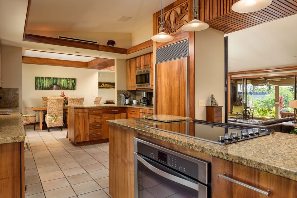 Enjoy cooking in this fully equipped gourmet kitchen featuring sleek wood cabinets, granite countertops, and modern appliances for a seamless vacation experience.