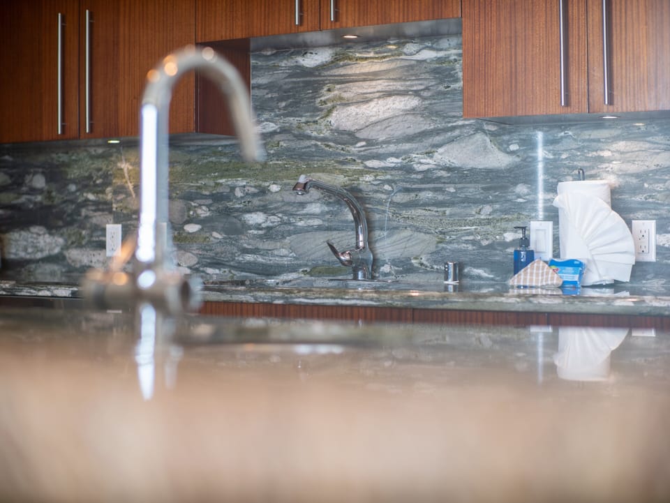 A modern kitchen complete with a sleek stone backsplash, high-end appliances, and thoughtful design touches that enhance your culinary experience in Maui.