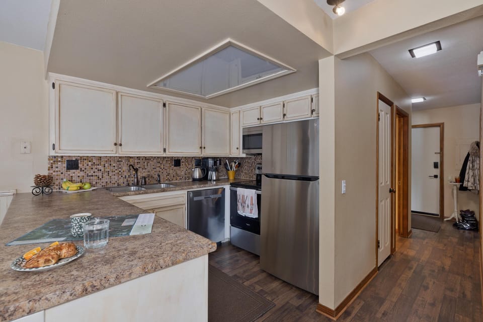 Prep meals in the well-equipped corner cookspace, dressed with hand-tiled splashboard, weathered ivory cabinetry, and chef-grade appliances.