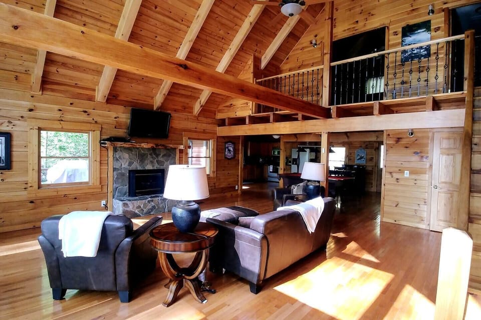 Open-concept living area featuring comfortable furniture, a seasonal gas fireplace, Smart TV, high ceilings, abundant natural light, and beautiful outdoor views — a bright and inviting space for relaxing and entertaining.