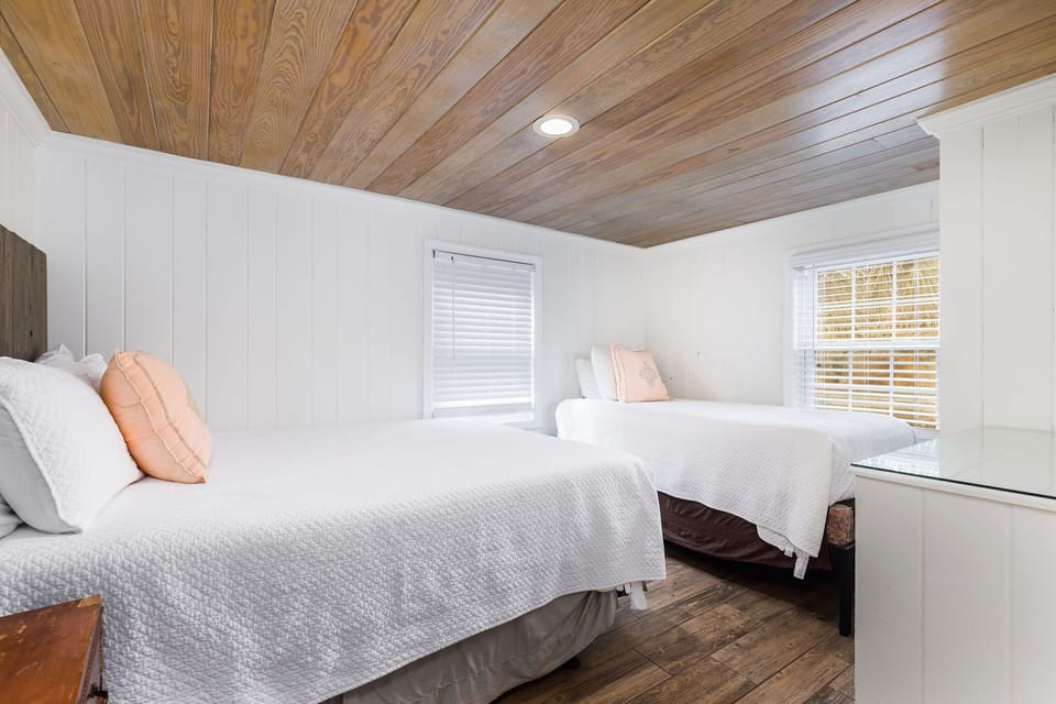 Bright beach-inspired primary bedroom with a queen bed plus dresser storage, ample closet space — steps from the beach