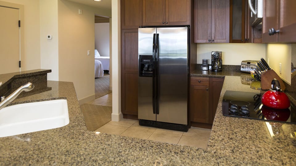 The stainless steel fridge in rich dark wood cabinetry in the kitchen.