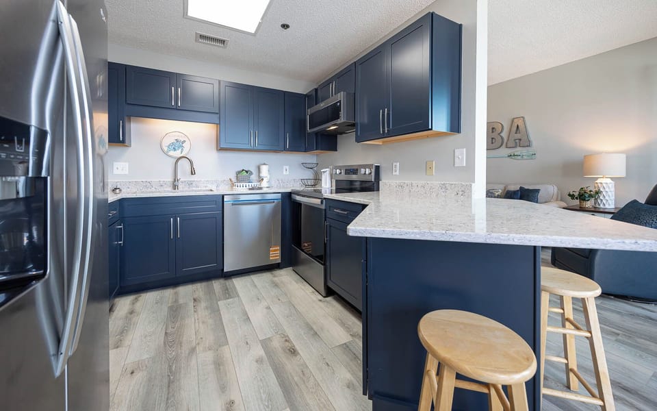 Prepare meals in the stylish kitchen featuring dark cabinetry, sleek appliances, and a convenient breakfast bar