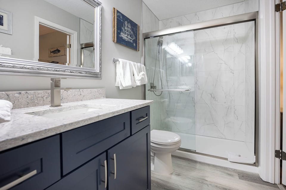 Stylish bathroom featuring a modern vanity, large mirror, and a walk-in shower for your comfort