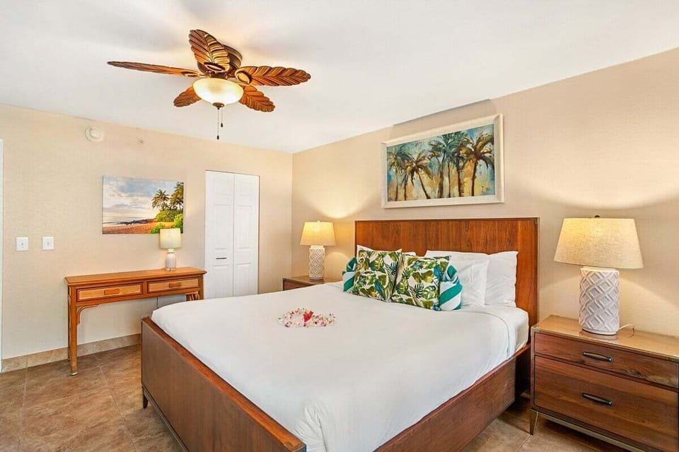 Large bedroom featuring a comfortable bed, tropical artwork, and ceiling fan for added comfort