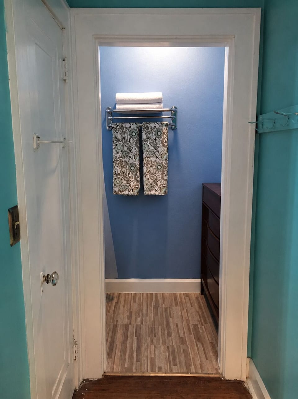 Hallway from bedroom to shower and tub, with dresser for added storage.