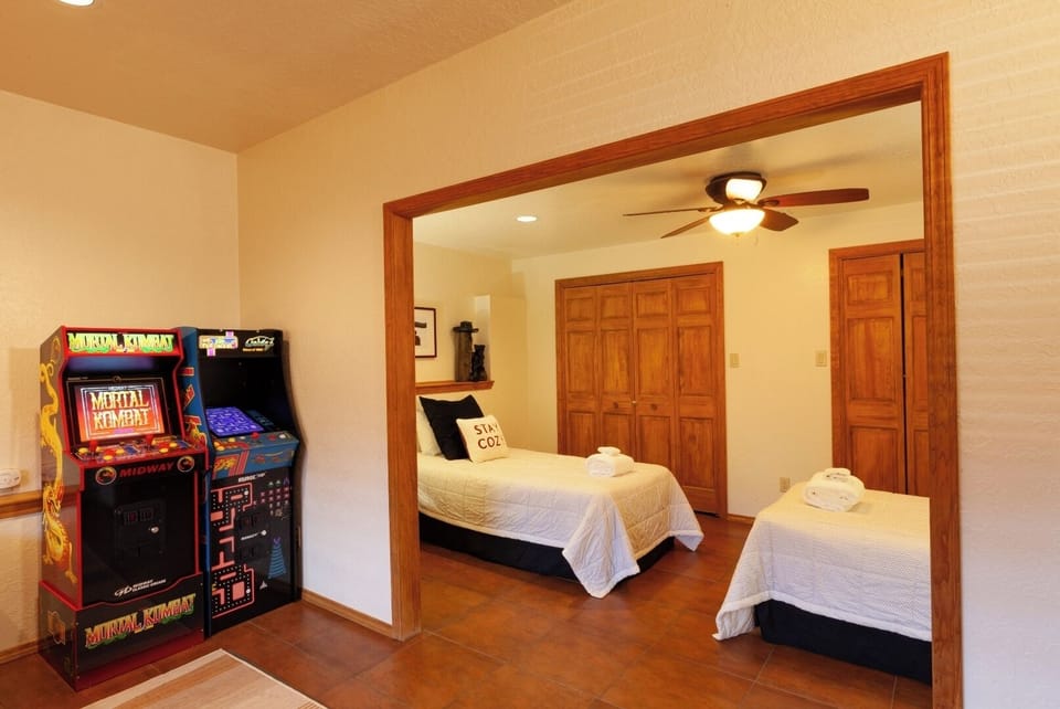 Relax in your private bedroom with comfy beds, warm wood tones, and classic arcade fun at your fingertips—perfect for unwinding after a day exploring.