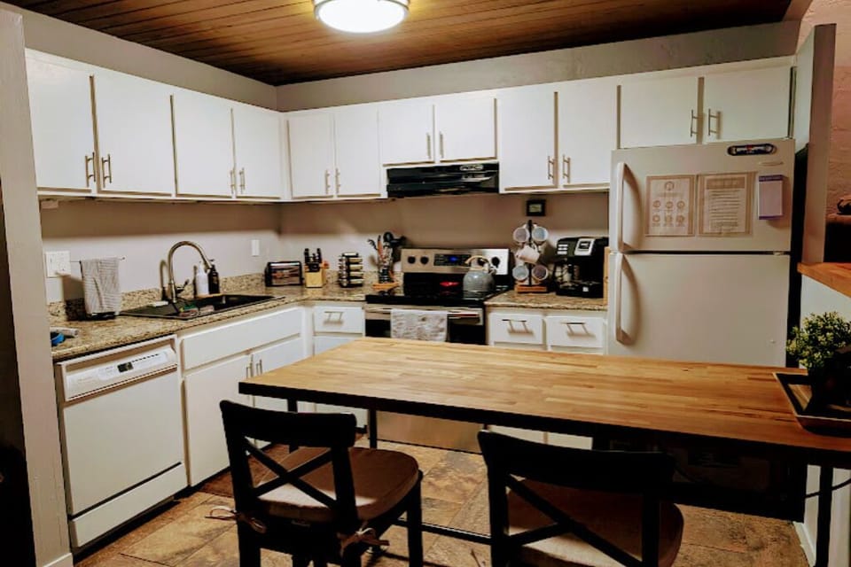 A warm and inviting kitchen filled with pots/pans, spices, coffee maker, etc