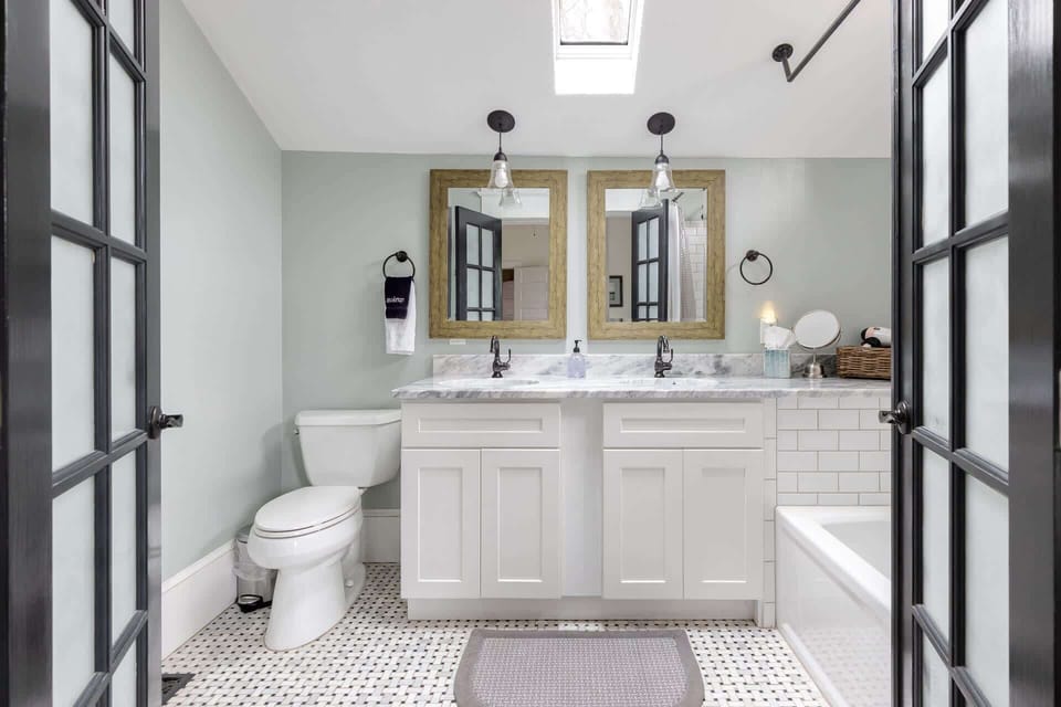 Skylights in the Downstairs primary bathroom make the granite counters, marble floors and subway tile shower walls a glowing, beautiful place to get ready