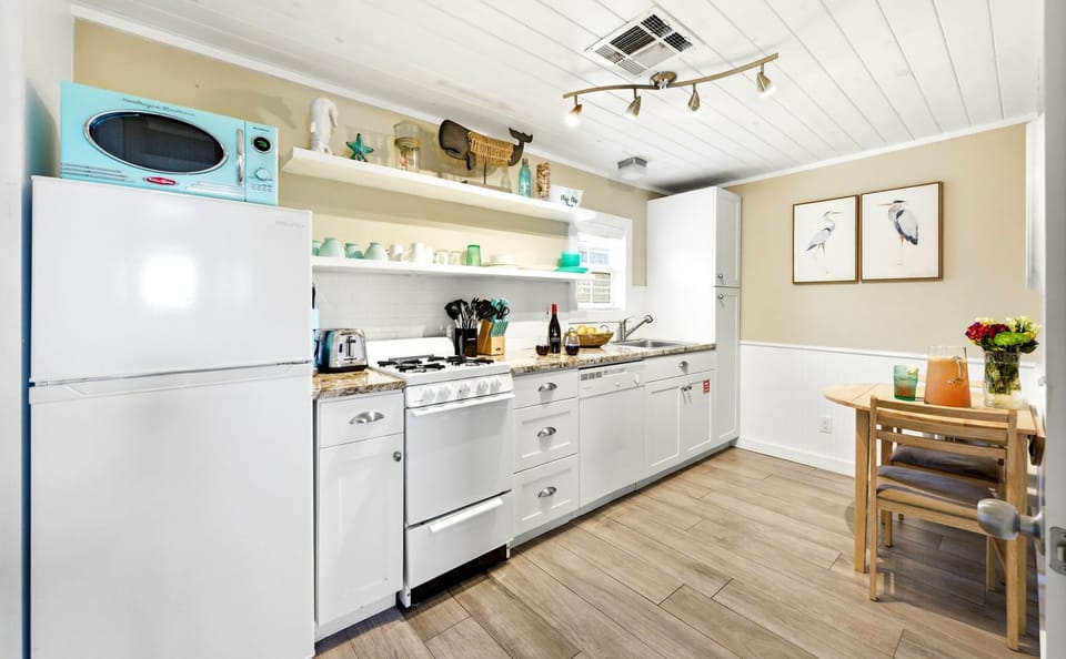 Fully equipped galley kitchen with a gas range, refrigerator, and dining table.