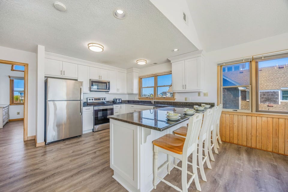 Prepare your favorite meals in this bright, fully-equipped kitchen with modern appliances, granite counters, and a breakfast bar perfect for casual dining.