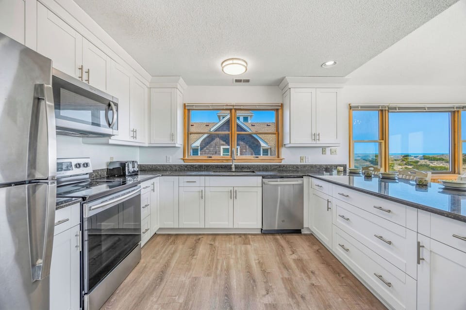 This bright, fully-equipped kitchen opens to stunning ocean views, inviting you to cook and unwind while waves shimmer in the distance.
