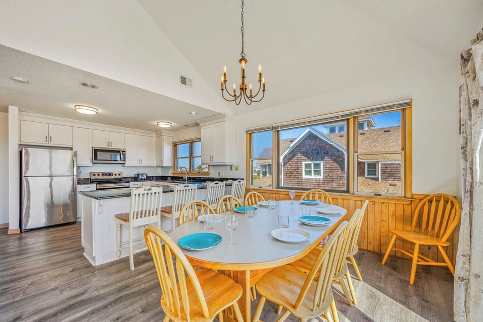 Bright, open kitchen and dining space where you'll gather for meals, with natural light streaming through large windows and room for everyone at the table.