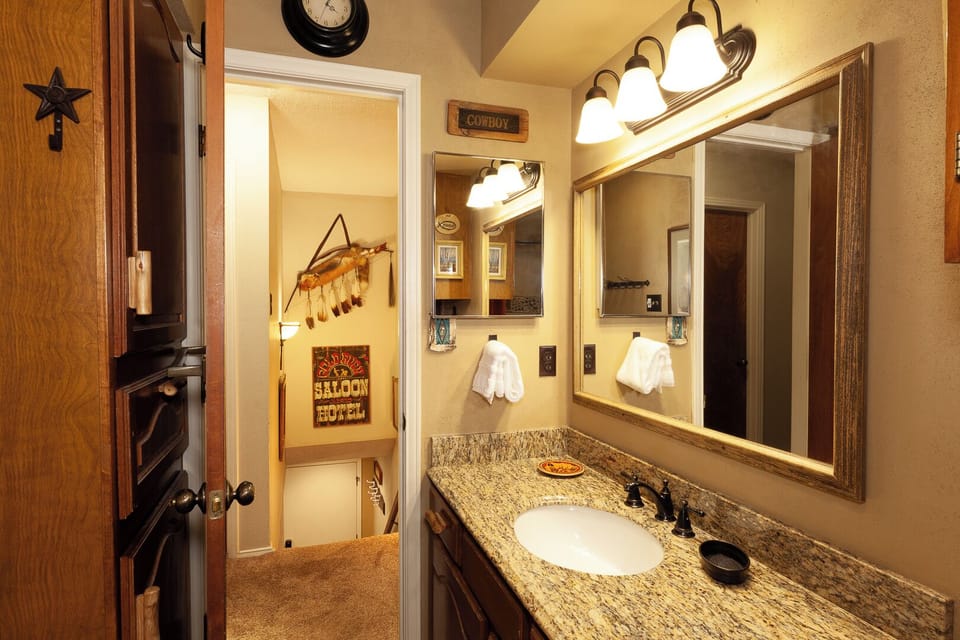 Enjoy your private bathroom with warm Western-themed touches, granite countertops, and bright vanity lighting that makes every morning feel welcoming.
