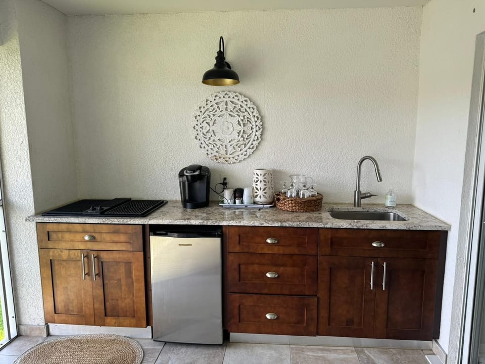 Granite countertop outdoor kitchen with electric grill, fridge, and sink.
