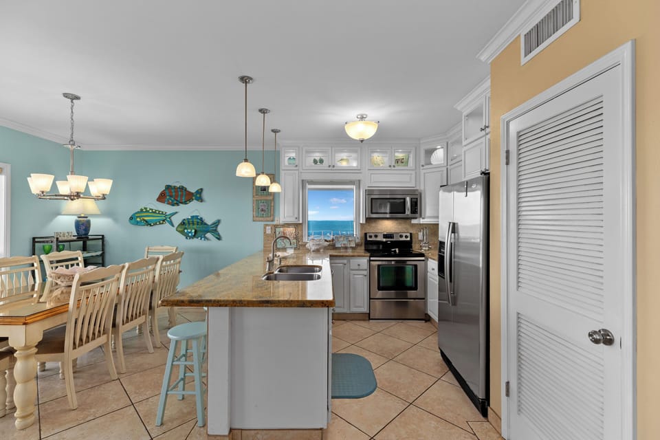 Kitchen with 4 counter stools.  Stainless appliances, cookware, toaster, griddle