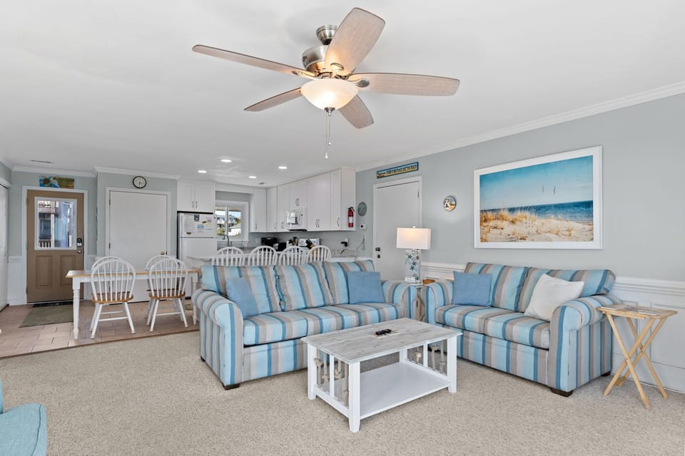 Relax in your coastal-themed living space with comfortable striped seating and an open-concept design connecting to your fully equipped kitchen.
