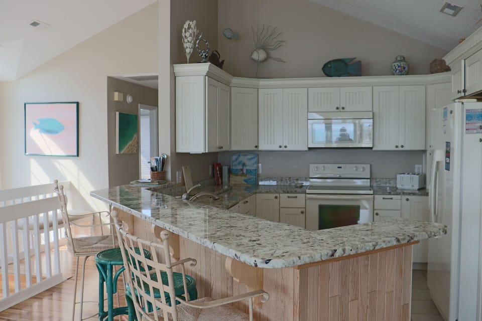 Your fully equipped kitchen features granite counters and coastal charm, perfect for preparing meals with friends.
