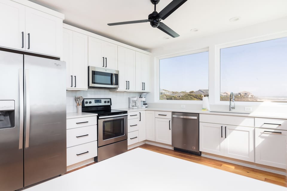 Cook with a view in this sleek, fully equipped kitchen featuring white cabinetry and ocean-facing windows