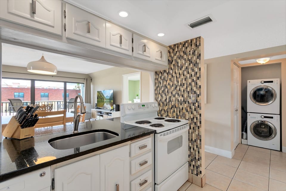 Fully equipped kitchen with stylish backsplash and convenient laundry area.