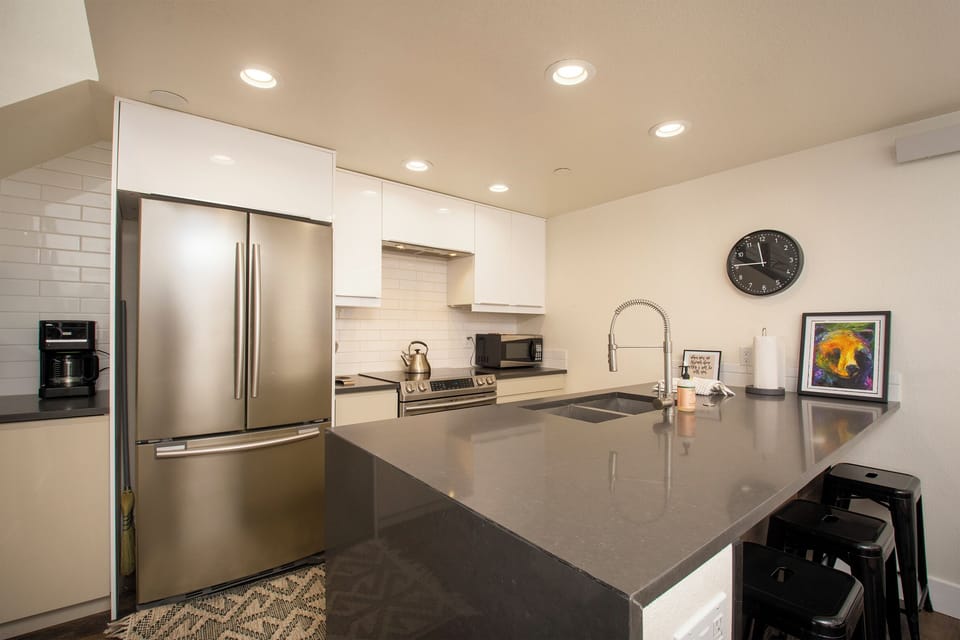 Your sleek modern kitchen awaits with stainless steel appliances, spacious quartz countertops, and everything you need to create memorable meals during your stay.