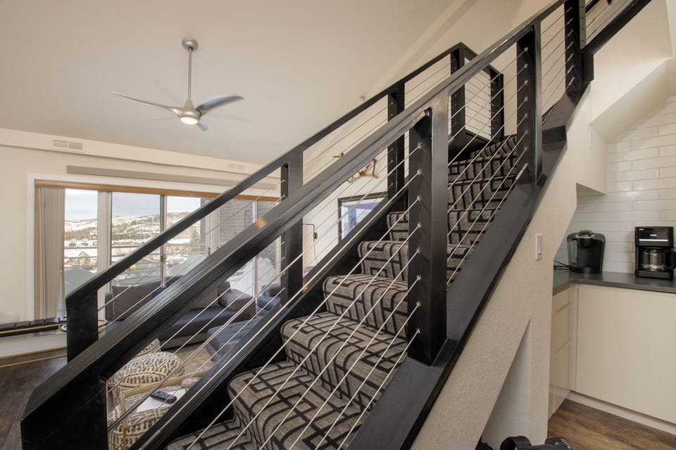 Modern staircase with sleek railings guides you to your upstairs retreat, while Colorado ski artwork adds mountain charm to your stay.