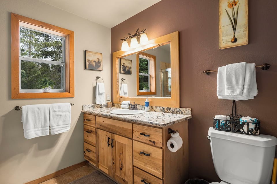 Freshen up in your stylish bathroom featuring granite countertops, warm wood vanity, and fluffy towels waiting for you.