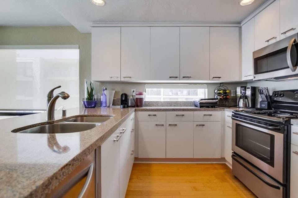 Kitchen with refrigerator, freezer, dishwasher, stove, oven, microwave, wine refrigerator, stainless steel appliances, quartz countertops, and ample cabinet and drawer space