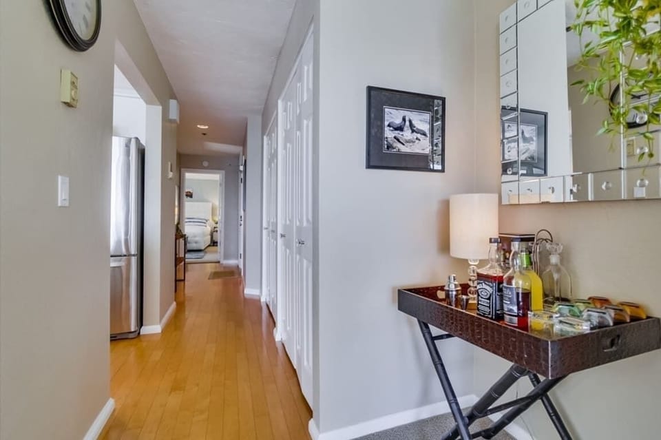 View of hallway with kitchen on the left, bedroom door at the end, and entrance to condo on the right. Closets on the right hold beach accessories and supplies.