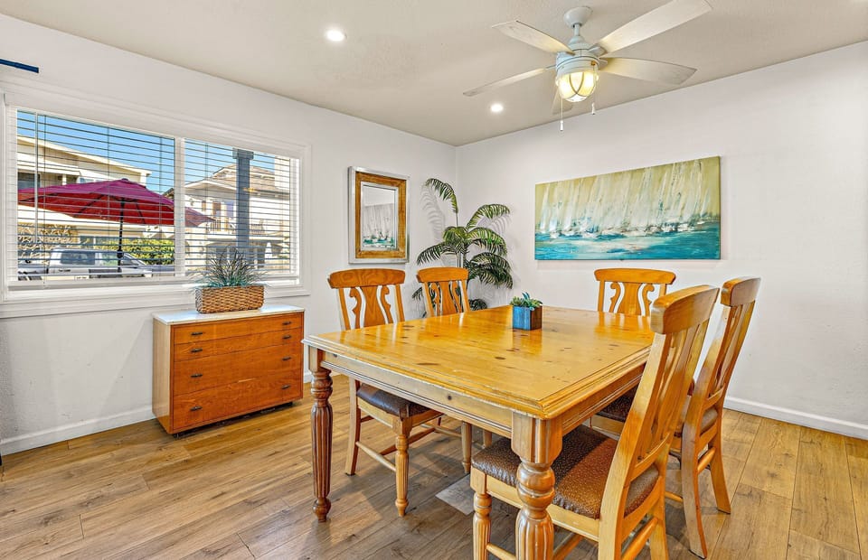 Dining area with seating for five, surrounded by natural light from large windows.
                