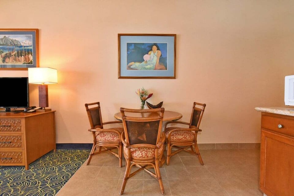 Dining and media space — gather around the table or unwind with TV and tropical artwork.