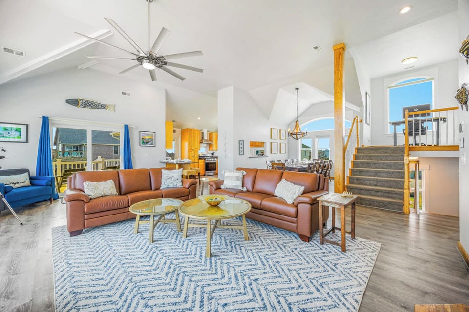 Relax in your spacious living area with soaring ceilings, coastal décor, and plush leather seating—perfect for gathering after a beach day.