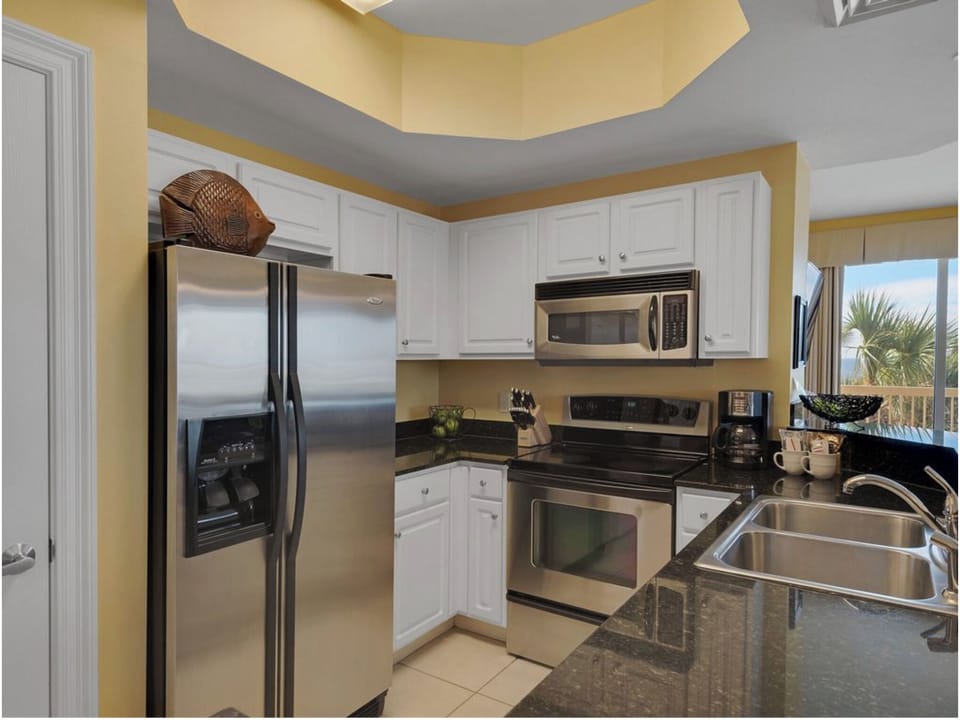 Your fully equipped kitchen awaits with granite counters, stainless appliances, and tropical views.