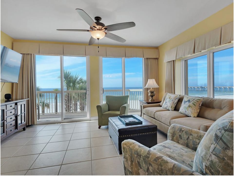 Relax in your bright living room with stunning ocean views through floor-to-ceiling windows and comfortable seating.
